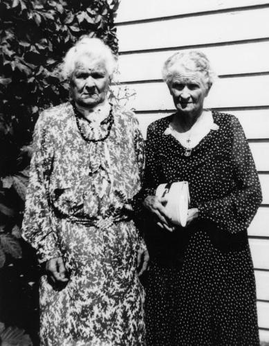 black and white photo of two women with grey hair and in floral print dresses, Harriet and Lavinia Orchard of Stroud in 1938
