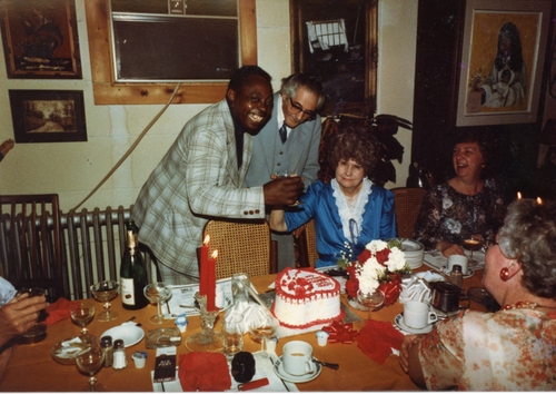 two men standing behind seated woman in informal portrait at a party