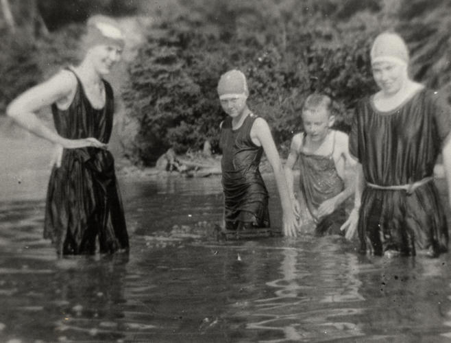 4 people swimming in a lake in old fashioned swimsuits