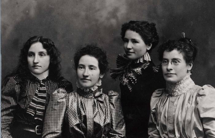 Portrait of 4 sisters in 1900, all 4 women are looking to their right. The three sisters on the right have their hair pinned  up but one sister on left has hair loose and down.