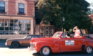 Image of the Cookstown Fair Queen riding in a vintage red car in 1990